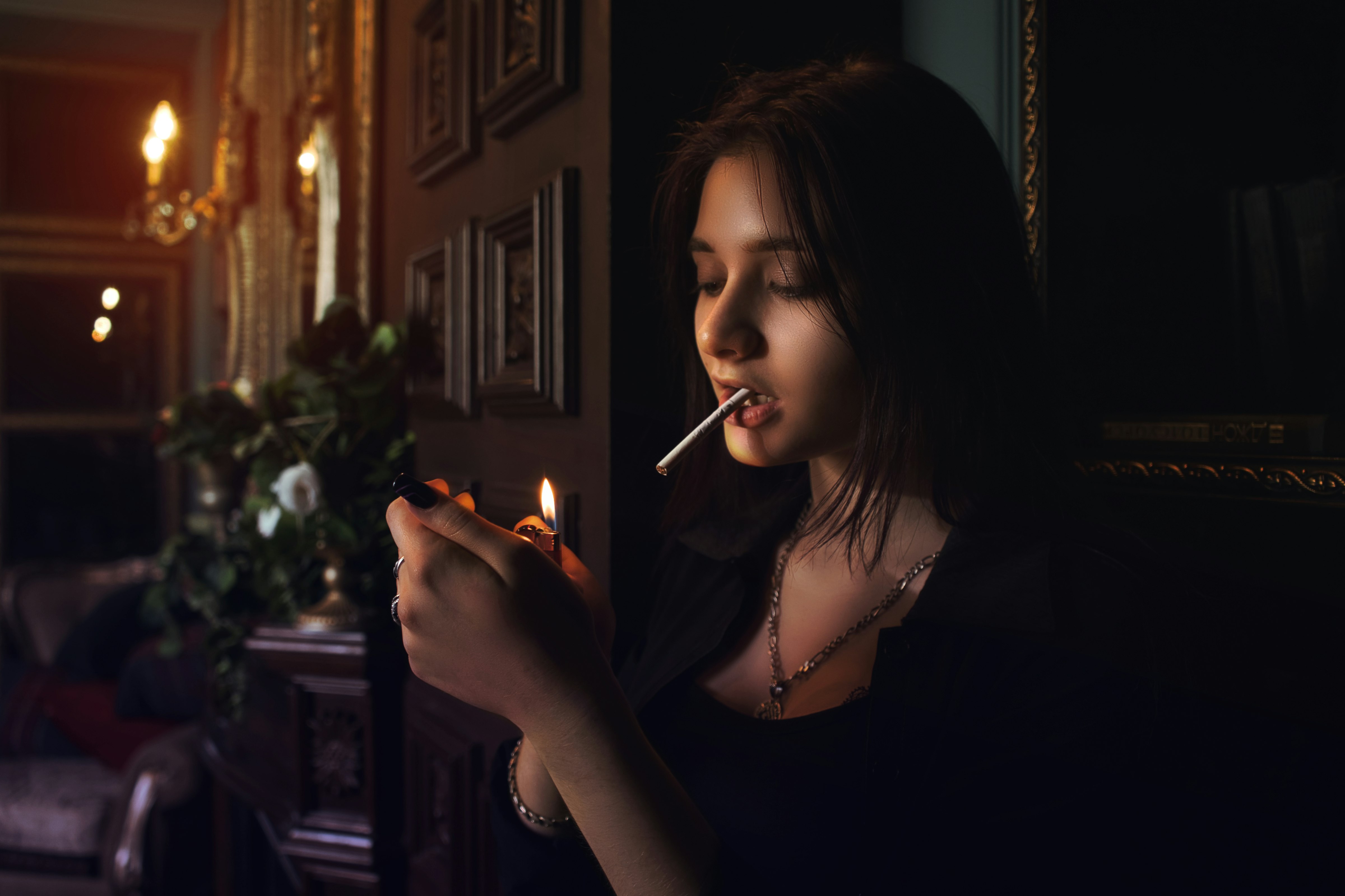 woman lighting cigarette stick in front of green plant